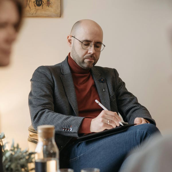 A therapist takes notes during a counseling session with clients in an office setting.